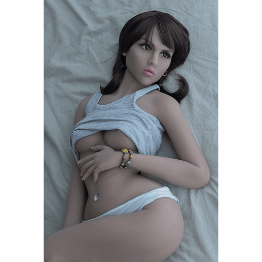 Muñeca Fiona acostada en la cama, levantando su camiseta para resaltar su busto. Su piel suave y su expresión seductora realzan su atractivo.