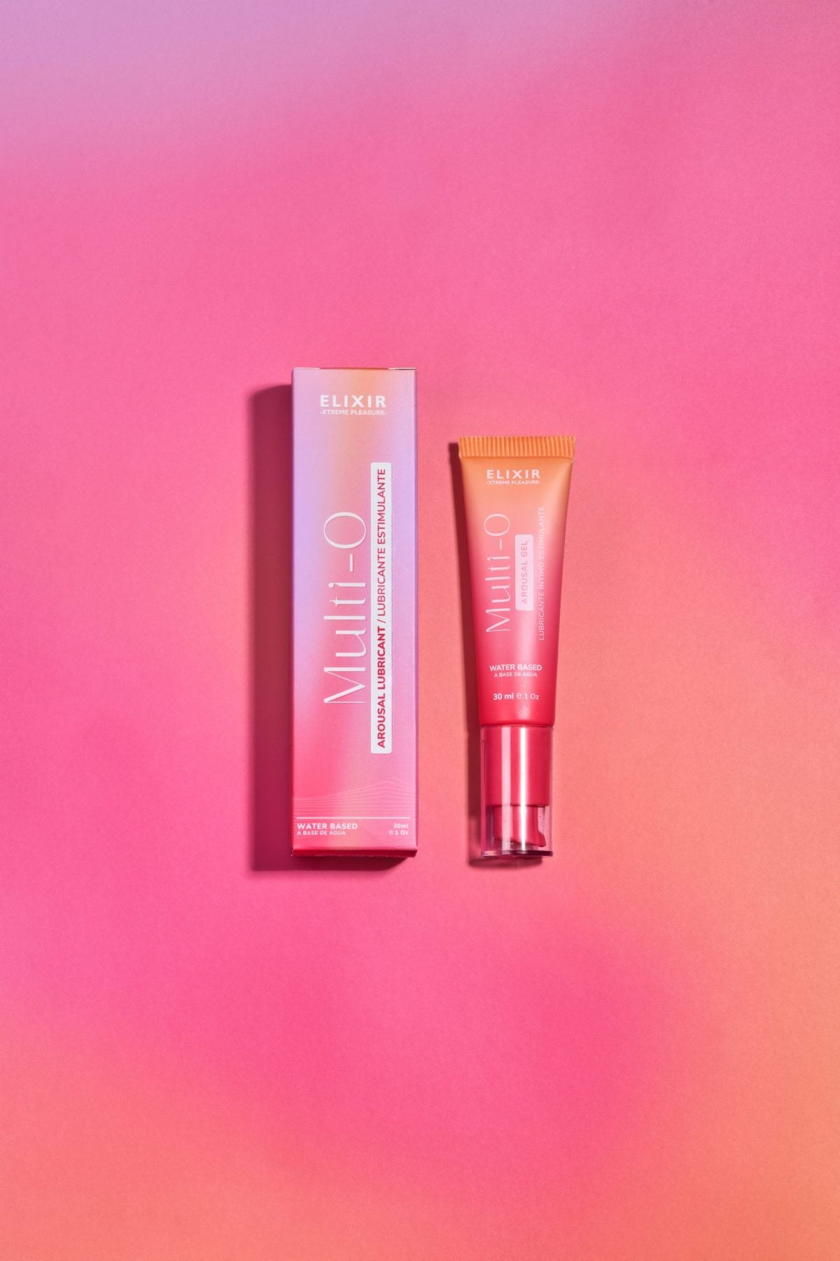 Vista superior del lubricante Multi O Elixir y su caja sobre fondo rosado, resaltando su presentación moderna y femenina.
