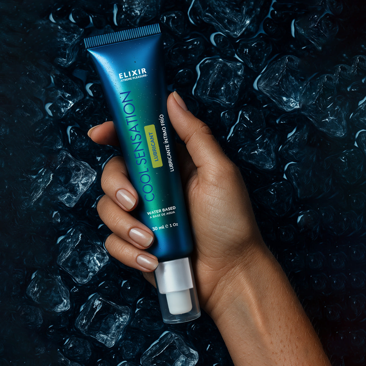 Lubricante frío Elixir Cool Sensation en una mano sobre fondo oscuro con hielo, evocando sensación intensa y refrescante.