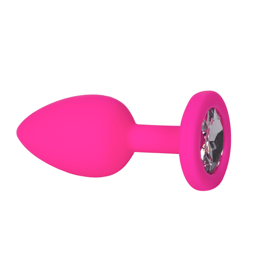 Plug anal pequeño de silicona médica en color rosa, con una superficie lisa y una joya transparente en la base, visto de perfil.