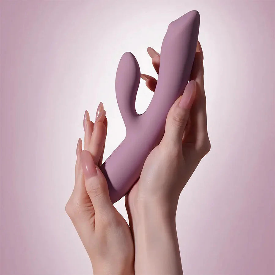 Vibrador Trysta NEO lila sostenido en manos, tamaño de 18.4 cm y estimulación dual para punto G y clítoris.
