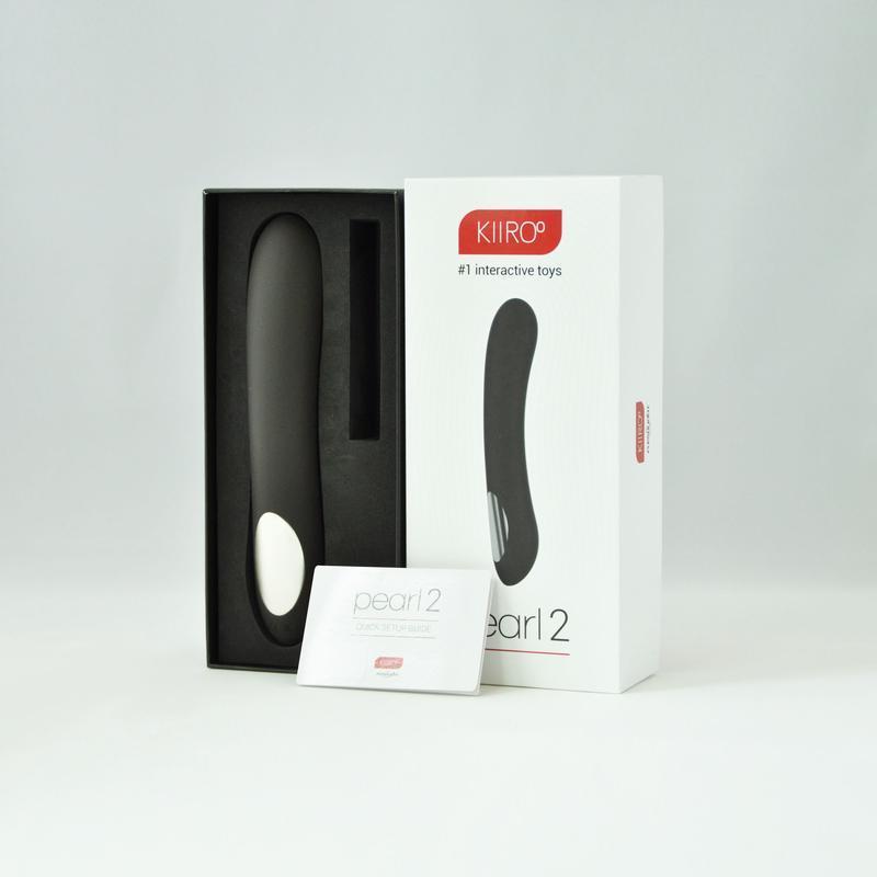 Vibrador Pearl 2 by Kiiroo en color negro dentro de su caja de presentación, acompañado de su manual de inicio rápido.